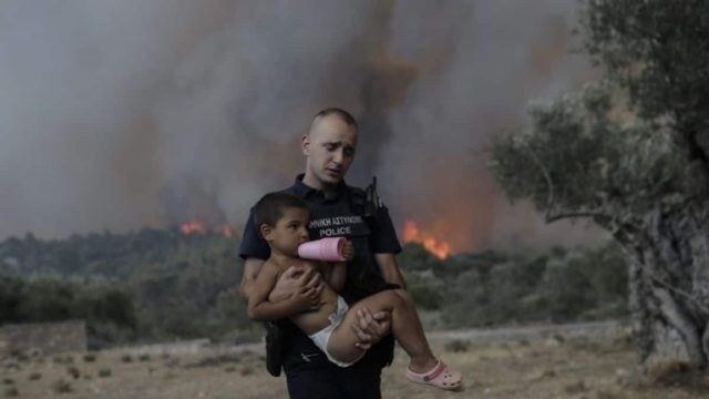 Όλη η Ευρώπη μιλάει για τις φωτιές στην Ελλάδα: Μονοπωλεί τα πρωτοσέλιδα ο αστυνομικός με το παιδί αγκαλιά γύρω από τις φλόγες (photos)
