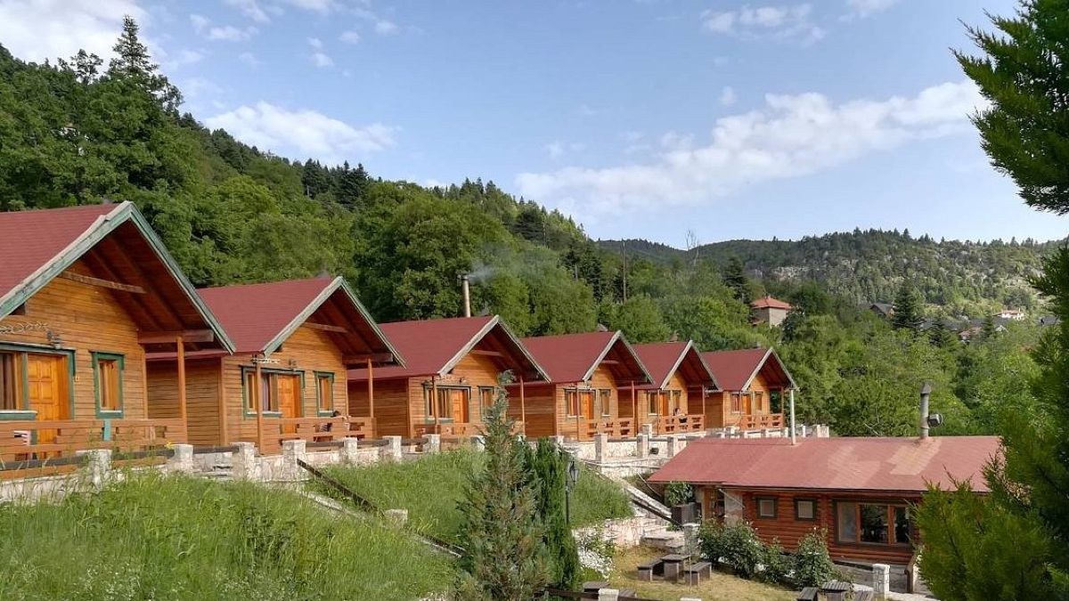 Ξύλινα παραδοσιακά σαλέ στο Καταφύγιο Ερμής, περιτριγυρισμένα από ψηλά έλατα στο δάσος της Ζήρειας